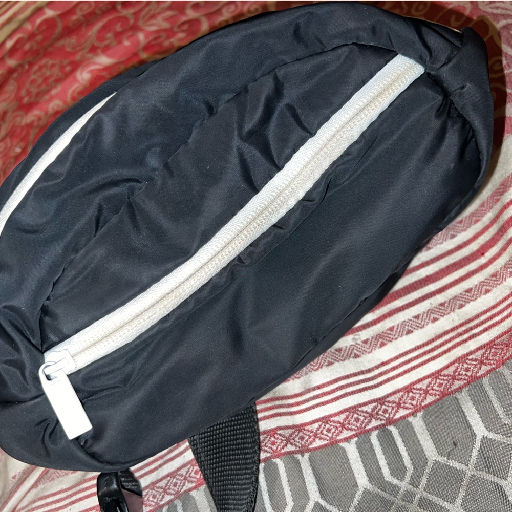 Simple yet cute black Fanny pack with white zipper and adjustable strap.